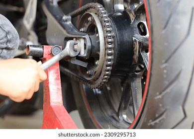 Mechanic's hand tightens a motorcycle chain - Powered by Shutterstock