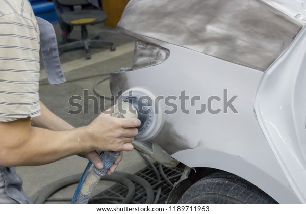 The\
mechanic\'s hand works the car part with a\
grinder