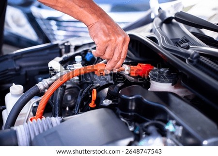 Mechanic's hands are checking engine equipment EV engine car. EV engine car engine block under hood electric vehicle high power and environmentally friendly zero emission. 