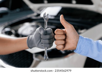 Mechanics is holding a spanner while the other is showing thumb up, Technic occupation. Automobile Repair Service Concept.