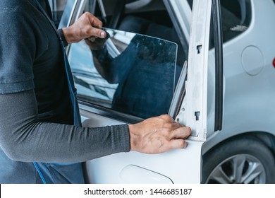 Mechanics Man Changing The Broken Windshield And Automobile Windshield Or Windscreen Replacement Of White Car In Auto Repair Shop