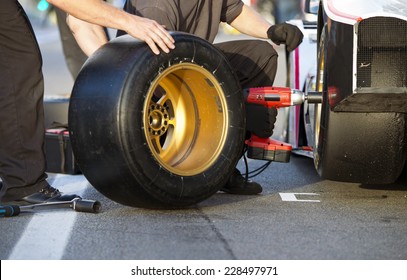 Mechanics Of A Pit Crew Changing The Slicks Of A Race Car During A Pitstop