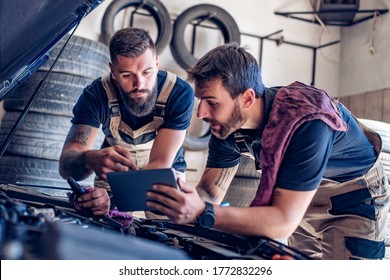 Mechanics Using Tablet To Fix Car At The Repair Garage.