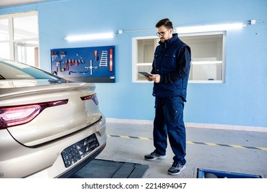 A mechanic's workshop worker using tablet to check on the car. - Powered by Shutterstock