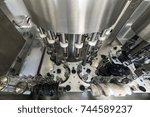 The mechanism of an automatic machine for filling and capping bottles. Factory for the production of alcoholic beverages.