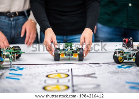 A mechatronic robot with artificial intelligence on wheels thrown by a woman's hands on a table with a canvas.
