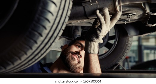 Mechatronics engineer examining the exhaust of a car in the car workshop
