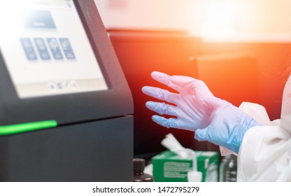 Med lab technologist using DNA sequencing equipment in science room. Chemist or scientist wearing blue medical glove working in hospital or university research laboratory. 