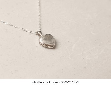Medallion pendant in shape of heart made of silver on chain. Love, romance, beautiful romantic gift heart medallion pendant, jewelry on the girl. Heart-shaped medallion pendant, silver.