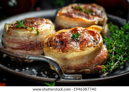 Medallions steaks from the beef tenderloin covered bacon on old meat butcher on Dark background.