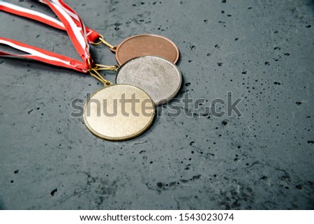 The medals lie on a dark stone background. Gold, silver and bronze medal on a dark background. The concept of tournaments and competitions. Victory, winning competitions.