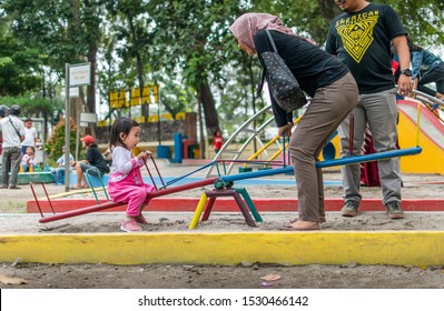 Medan, Indonesia - October 13, 2019 : Little Asian Girl Playing See Saw With Her Mother