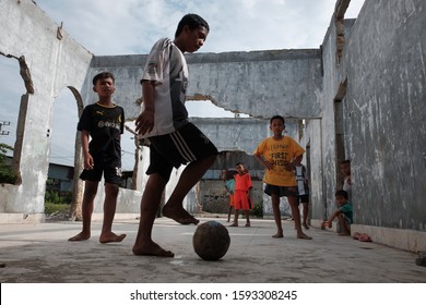 Medan, North Sumatra-December 2019: A Group Of Indonesian Boys Play Soccer Barefoot On A Concrete Floor Of An Abandoned And Unused House In Belawan Suburb, Medan.