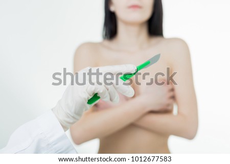 Medecine scalpel on the background of the female breast
