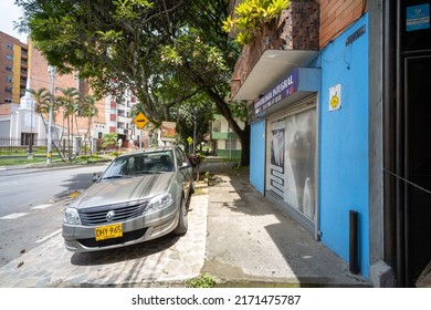 Medellin, Antioquia, Colombia - June 2 2022: Grey Car Parked In Residential Neighborhood Street And Sidewalk With Blue House