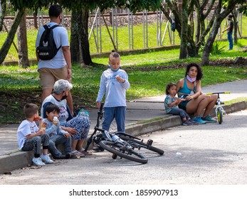 Medellin, Antioquia / Colombia - November 15 2020: Latin Grandmother With Her Grandsons Are Sitting On The Sidewalk Eating  An Icecream