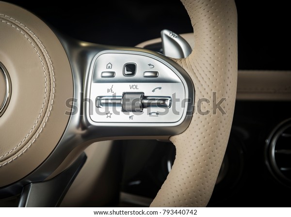 media\
control buttons on the white leather steering wheel, modern luxury\
car interior details, hands free, luxury\
car