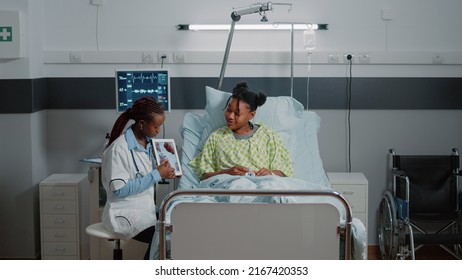 Medic Holding Tablet With Cardiology Figure To Show Diagnosis To Woman In Bed. Medical Physician Explaining Cardiovascular Exam Results On Device Screen To Sick Patient. Healthcare Checkup