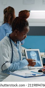 Medic Holding X Ray Scan On Tablet For Consultation With Patient In Cabinet. Doctor And Ill Person Looking At Gadget Screen With Radiography For Healthcare Examination And Checkup Visit.