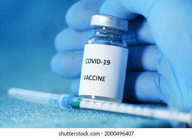 A medic holds an ampoule of Sputnik V coronavirus vaccine in a protective blue medical glove