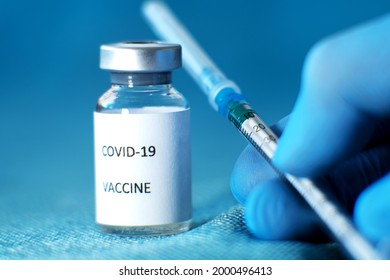 A medic holds an ampoule of Sputnik V coronavirus vaccine in a protective blue medical glove