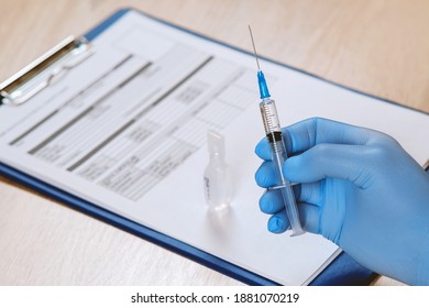 A medic holds a syringe with the Sputnik-V coronavirus vaccine in a protective blue medical glove.
