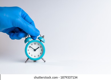 Medic Person Holding Alarm Clock Over Grey Background. Copy Space. Studio Shot. Minimal. Medicine Time Concept.