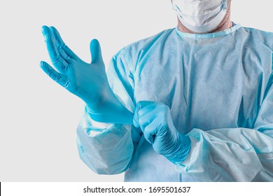 A Medic In A Protective Suit Puts On Medical Gloves. Personal Protection For The Coronavirus Pandemic Infection Virus Covid 19. Protective Medical Equipment For Laboratories, Research Hospitals