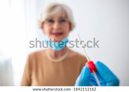 Medic taking sample for coronavirus testing. Coronavirus test. Medical worker in protective suite taking a swab for corona virus test, potentially infected senior woman 