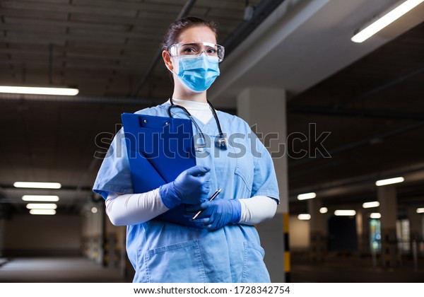 Medical 999 EMS worker wearing PPE\
uniform,safety goggles,face mask,holding clipboard at mobile test\
center site,PCR Coronavirus COVID-19 virus disease detection in\
drive-thru check control\
facility