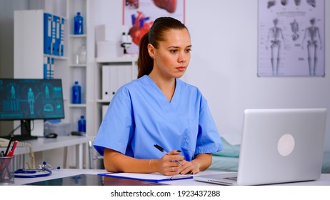 Medical assistant typing on laptop and taking notes on clipboard in hospital office. Healthcare physician in medicine uniform writing list of consulted, diagnosed patients, making research. - Powered by Shutterstock