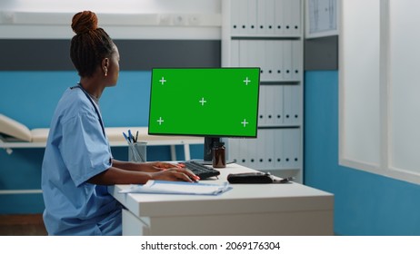 Medical Assistant Using Horizontal Green Screen On Computer In Cabinet. Woman Working As Nurse Looking At Mockup Template With Isolated Background And Chroma Key On Monitor Display.