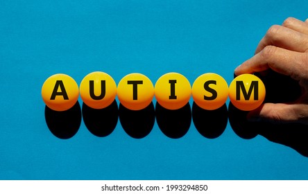 Medical And Autism Symbol. The Concept Word 'autism' On Orange Table Tennis Balls On A Beautiful Blue Background. Doctor Hand. Medical, Psychological And Autism Concept.