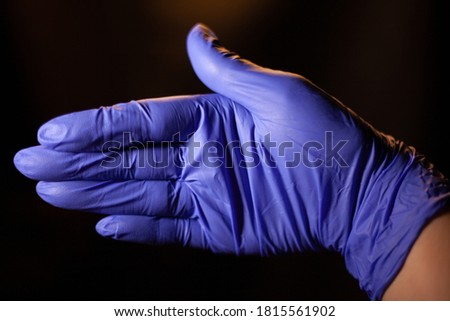 Medical blue lactation glove in women's hand on a black background