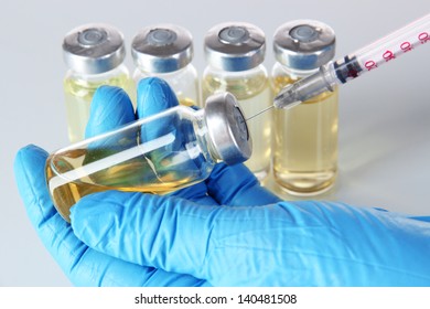 Medical bottles and syringe in hand on gray background