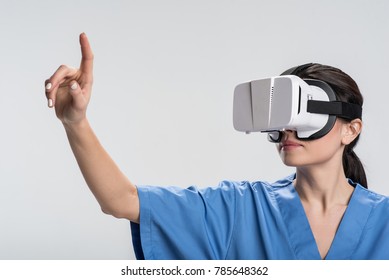  Medical Breakthrough. Smart Pleasant Female Doctor  Dressing In VR Glasses And Stretching Finger  While Conducting Test In Virtual Reality