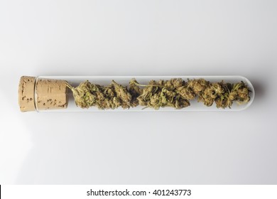 Medical cannabis buds in glass test tube closed with cork on white background from above