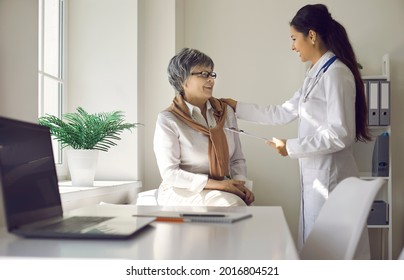 Medical Care For The Elderly And The Doctor's Interaction With The Patient. Caring Female Doctor Cheerfully Talks And Comforts An Elderly Woman Who Came To The Clinic For A Medical Examination.