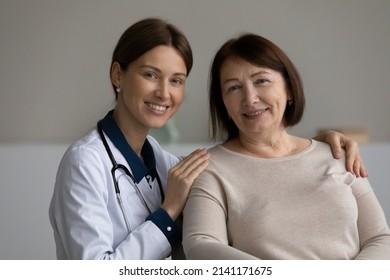 Medical care. Headshot portrait of two females young doctor and elderly patient pensioner on appointment at clinic. Happy confident attending physician hug shoulders of mature lady client help support - Shutterstock ID 2141171675