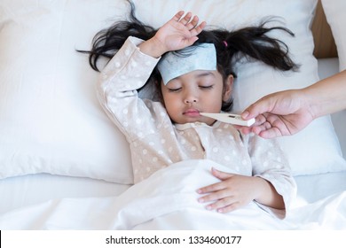 Medical Check Up And Treatment Concept. Mother Is Measure The Temperature Of Little Asian Kid Girl. Sick Child With Fever And Illness In Bed.