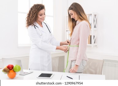 Medical checkup. Nutritionist measuring female patient's waist during consultation in office, copy space - Powered by Shutterstock