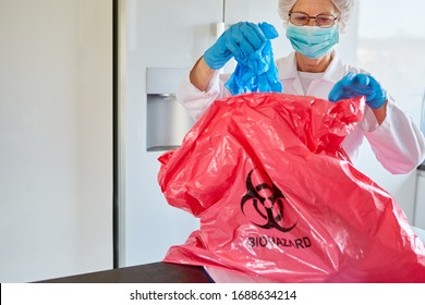 Medical cleaner with protective clothing disposes of infectious waste in a clinic during a Covid-19 coronavirus epidemic