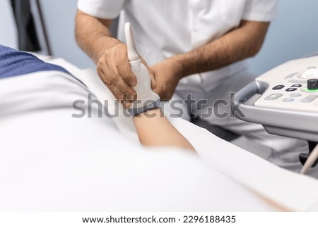 At the medical clinic, Caucasian male doctor doing the doppler ultrasound test evaluation of arteries and veins on a female patient