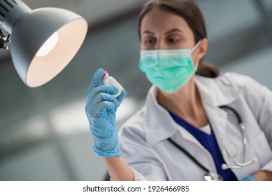 In the medical clinic, vaccination of the population against covid-19 has begun, the doctor shows a bottle with the vaccine. - Powered by Shutterstock