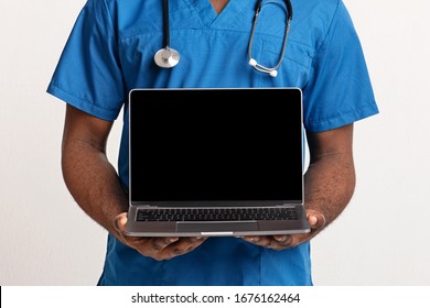 Medical Clinic Website. Blank Laptop Screen In African American Doctor Hands Over White Background, Close Up