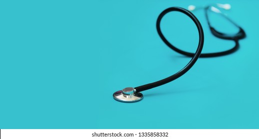 Medical concept background. Black stethoscope in shallow depth-of-field on blue background with side copy space for text area.