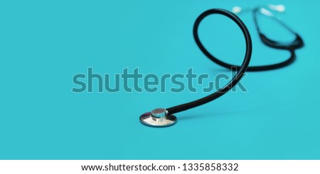 Medical concept background. Black stethoscope in shallow depth-of-field on blue background with side copy space for text area.