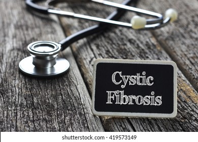 Medical Concept- Cystic Fibrosis word written on blackboard with Stethoscope on wood background