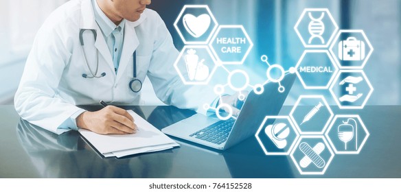 Medical Concept - Doctor Working In Hospital With Computer And Writing Paperwork Illustrated With Medical Icons Pop Up From Doctors Hand About Healthcare Pharmacy Business And Doctoral Education.