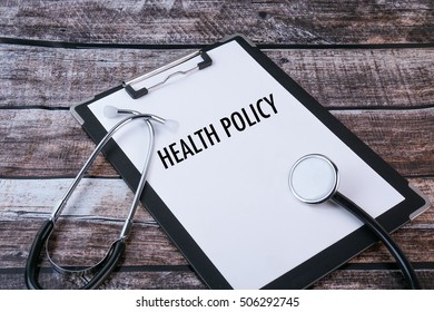  Medical Concept : Health Policy Written In Clipboard With Stethoscope On Wooden Background.                          